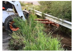 Modified Skid Steer removing debris from underneath guardrail