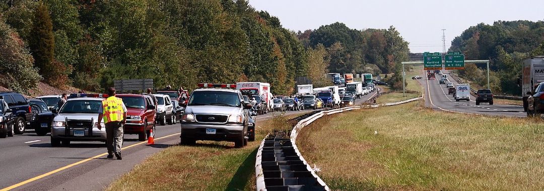 Image of backed up traffic and first responder in neon vest standing on highway