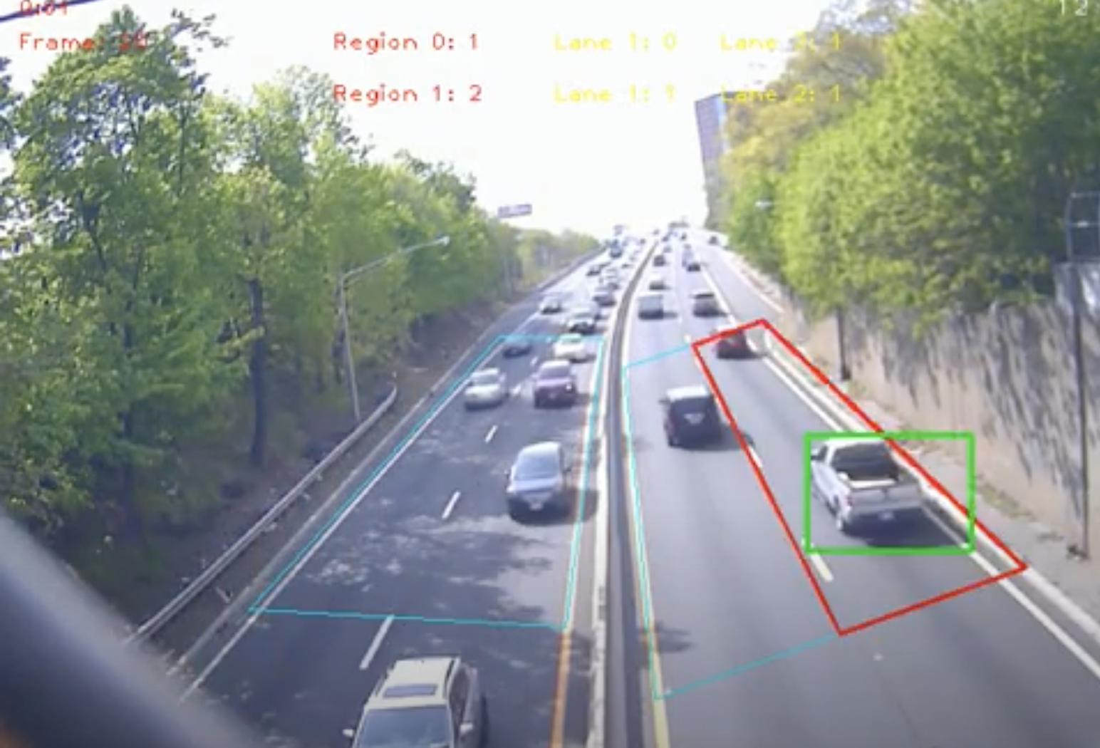 Video image of interstate highway with bidirectional traffic and AI identifying vehicles using green and red boxes