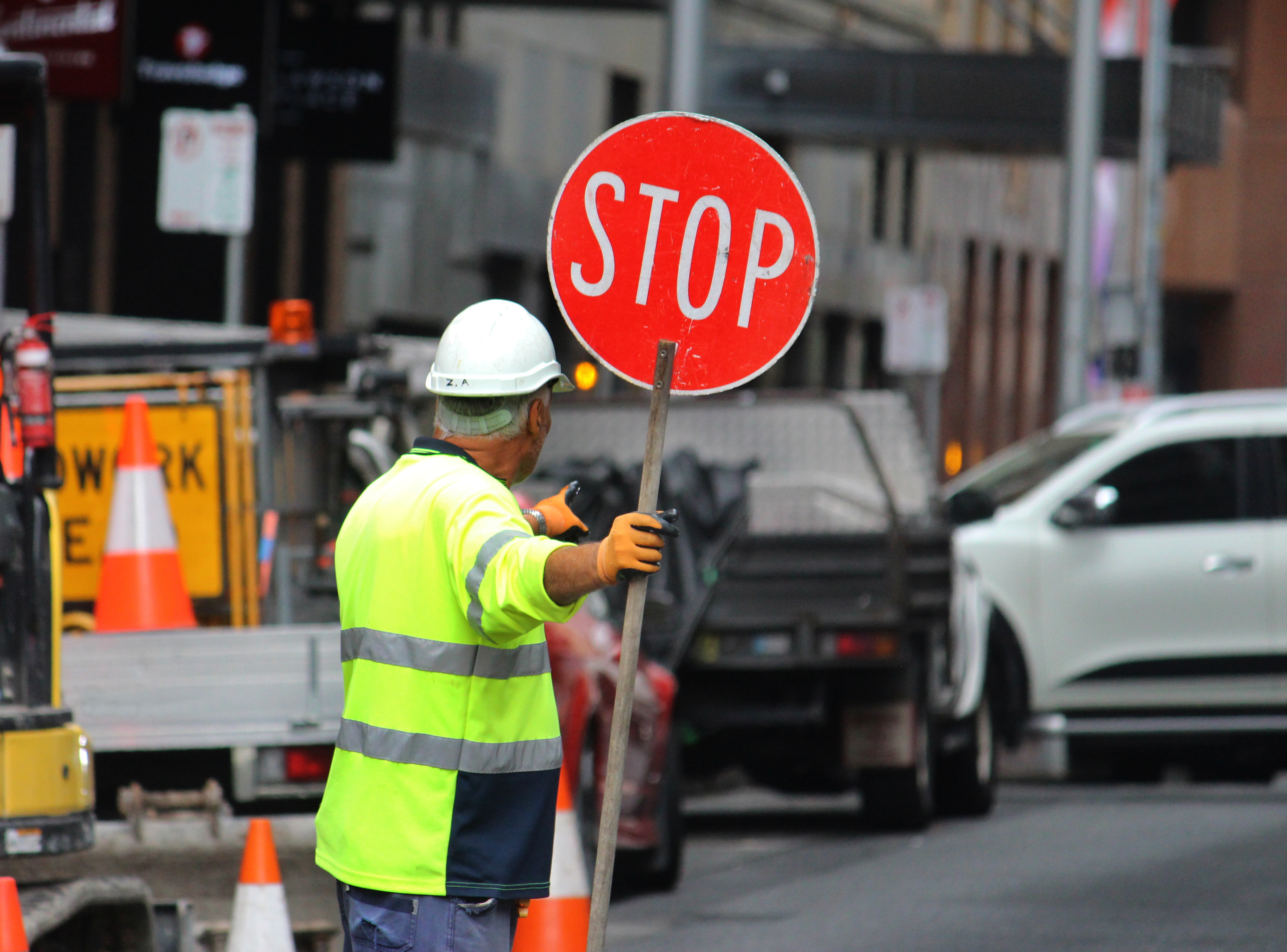 Male construction road worker holding a stop sign and directing